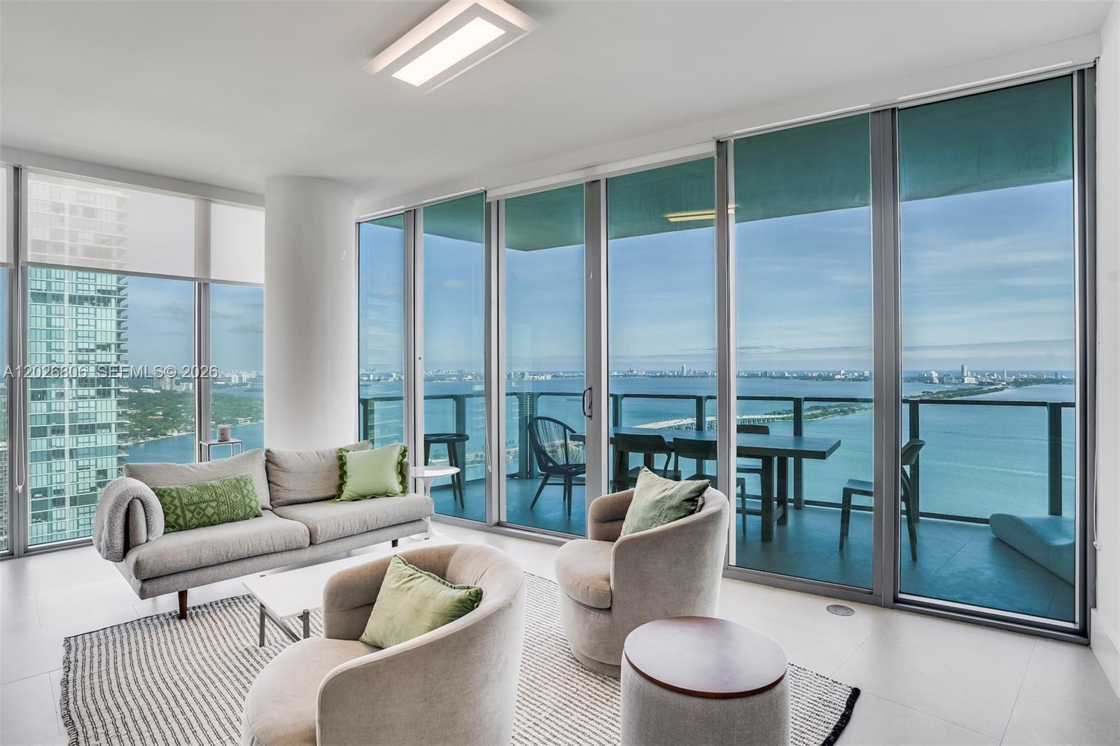 A modern living room features floor-to-ceiling windows with a balcony overlooking the ocean — 2900 NE 7th Ave # 3702, Miami FL 33137, MIAMI, FL