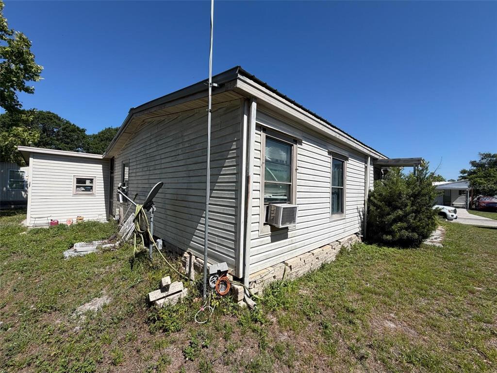 The exterior of a light-colored, single-story home with a metal roof and window air conditioner — 3633 LAZY LAKE DRIVE S UNIT 3, LAKELAND, FL