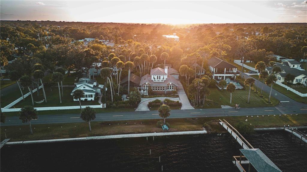 An aerial view shows a waterfront house with a circular driveway surrounded by palm trees — 4946 HALIFAX DRIVE, PORT ORANGE, FL