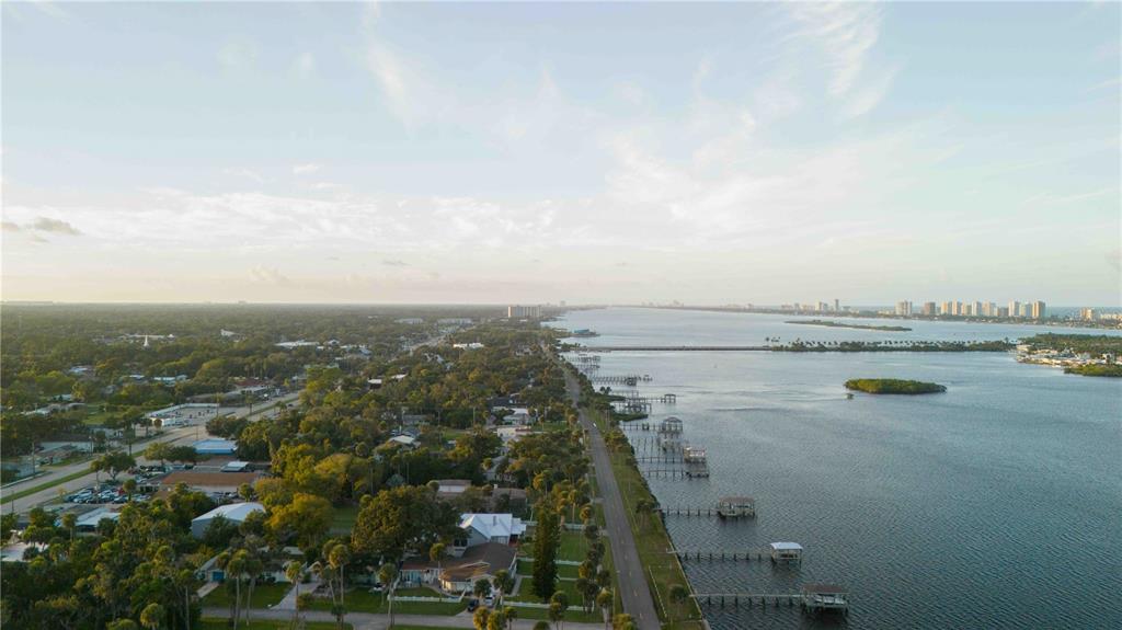 An aerial view shows a coastal road lined with houses and docks along the water — 4946 HALIFAX DRIVE, PORT ORANGE, FL
