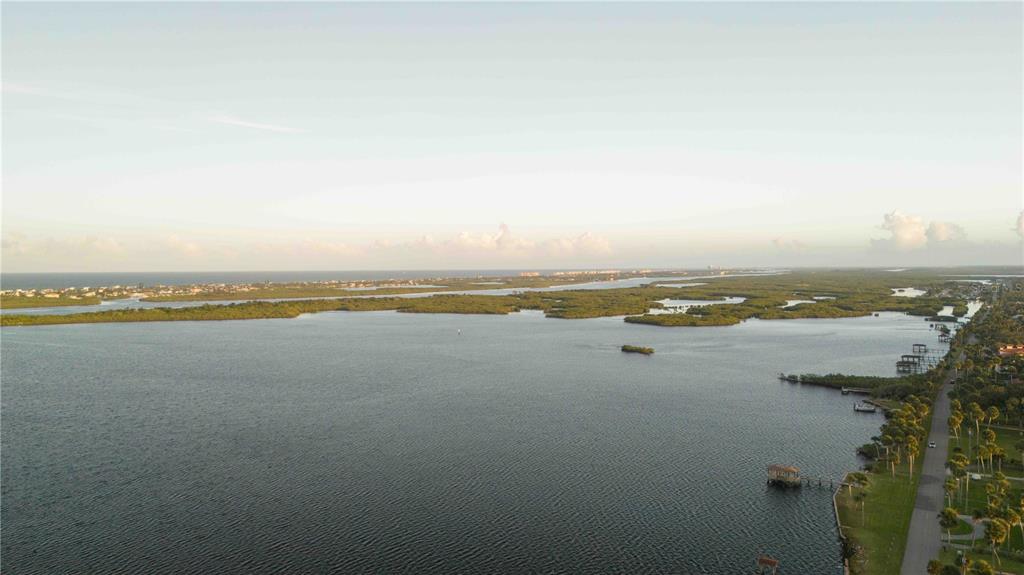 An aerial view shows a large body of water, mangrove islands, and a coastal road — 4946 HALIFAX DRIVE, PORT ORANGE, FL