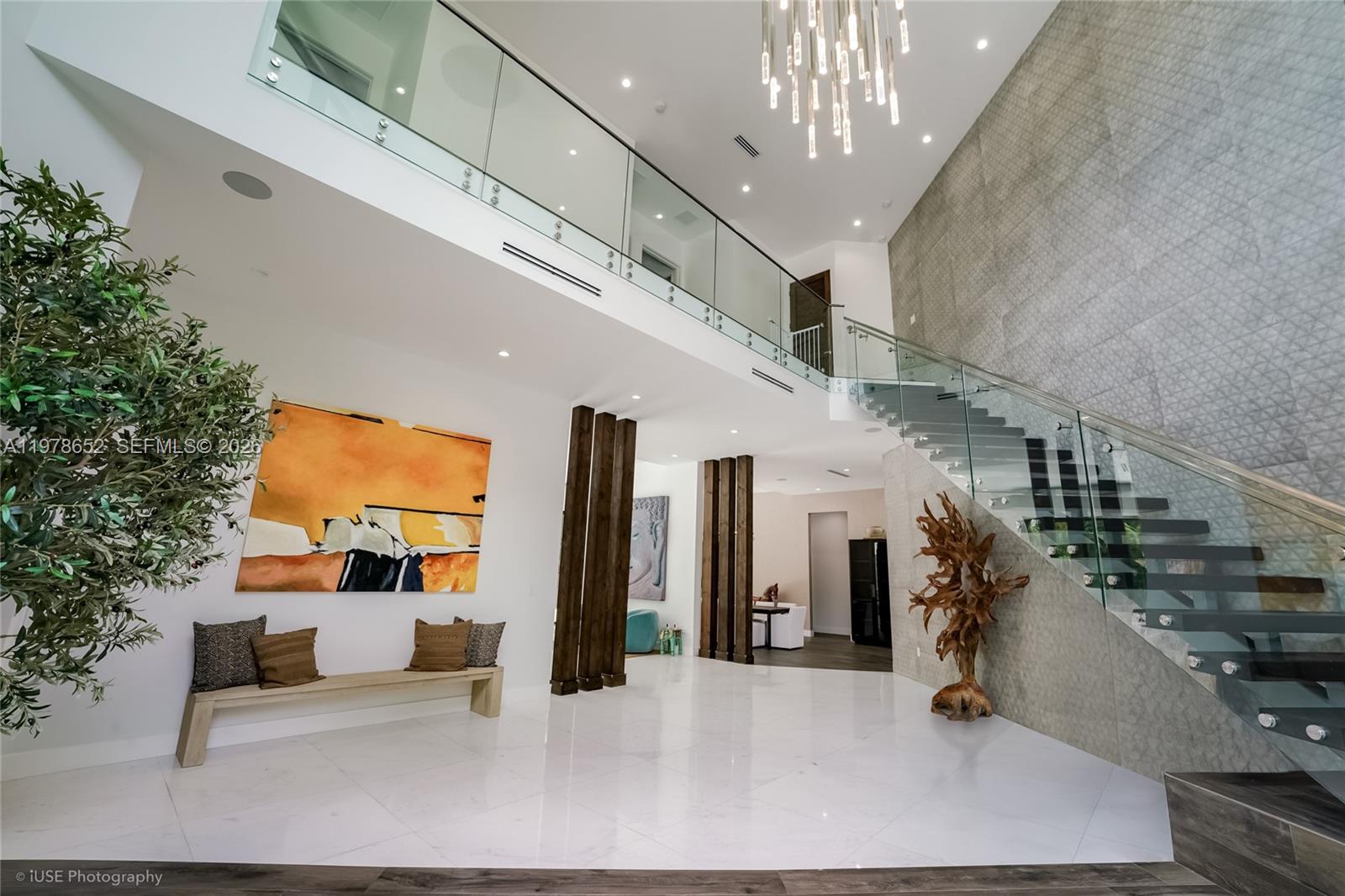 A modern foyer features a floating staircase, glass railings, and a large abstract painting — 56 Samana Dr, Miami FL 33133, MIAMI, FL