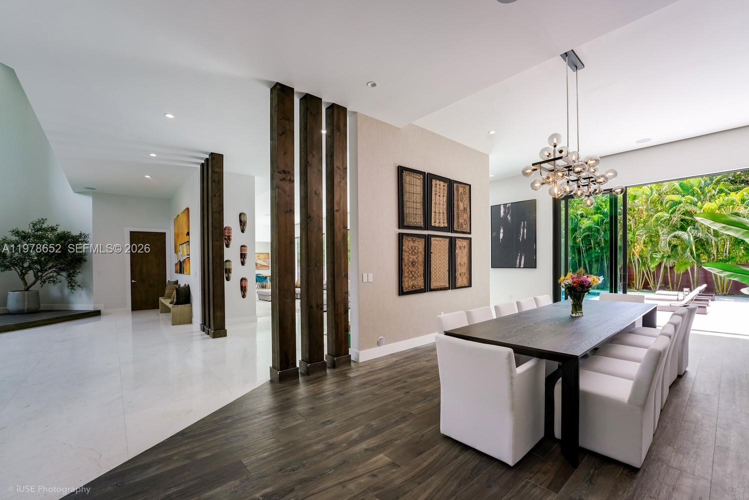 A dining room features a long wooden table, white chairs, and decorative wooden room dividers — 56 Samana Dr, Miami FL 33133, MIAMI, FL