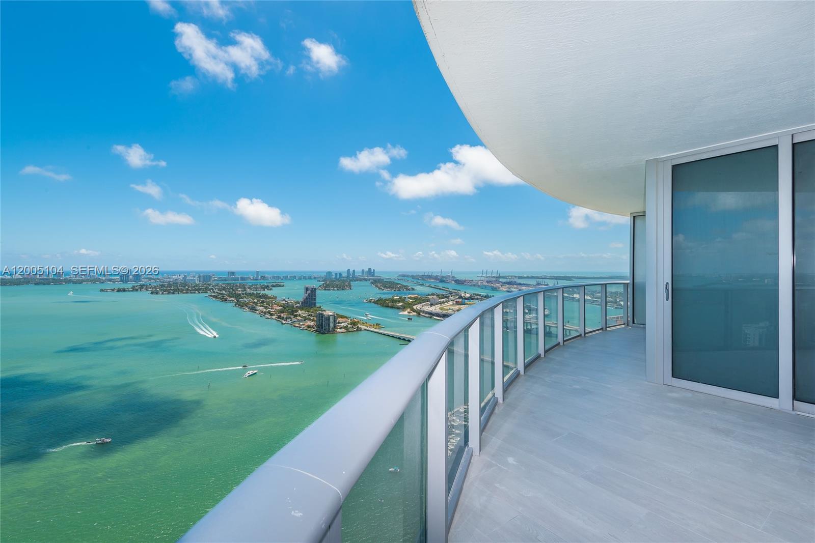 A high-rise balcony with a glass railing overlooks a bay with islands and boats — 488 NE 18th St # 4515, Miami FL 33132, MIAMI, FL