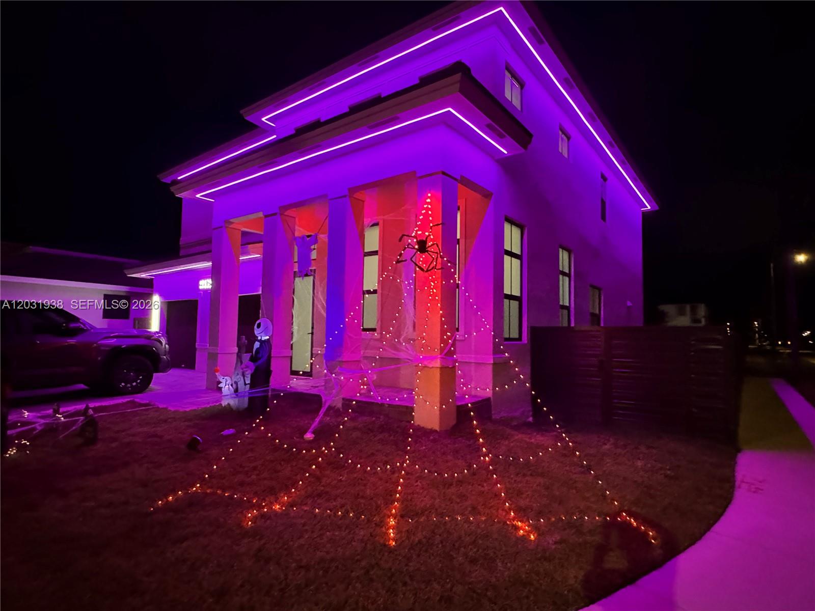 A two-story house exterior is decorated with purple roof lighting and a light-up spiderweb — 14405 SW 13th Ter, Miami FL 33184, MIAMI, FL