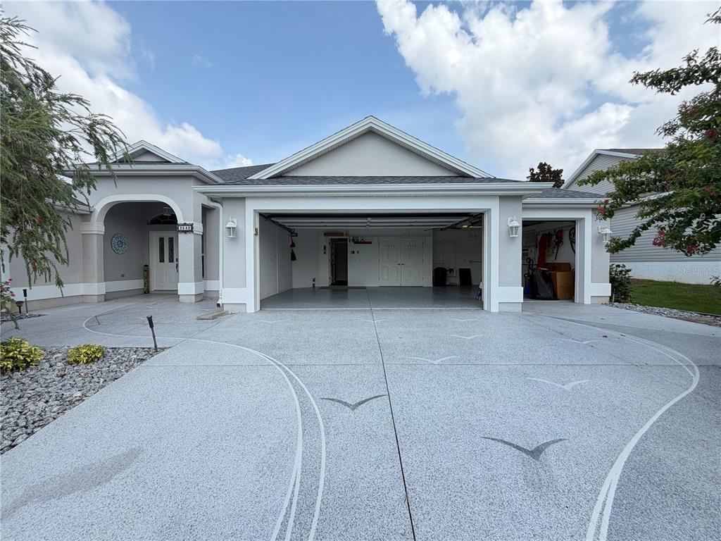 The exterior of a house features a gray driveway with seagull patterns and a three-car garage — 2542 FLINTSHIRE AVENUE, THE VILLAGES, FL