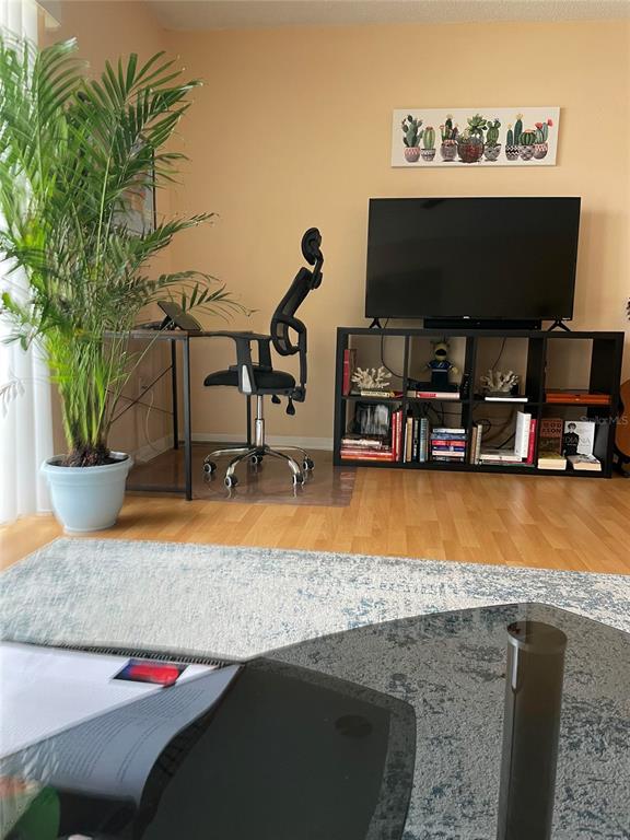 A living room features a desk, an office chair, a television on a shelf, and plants — 239 S MCMULLEN BOOTH ROAD UNIT 38, CLEARWATER, FL