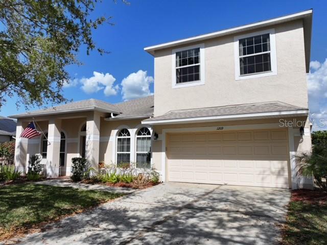A two-story house with a beige stucco exterior, a two-car garage, and an American flag — 1209 CASTLEPORT ROAD, WINTER GARDEN, FL