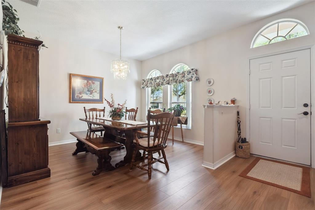 A dining area with a wooden table, chairs, bench, and a white front door — 1209 CASTLEPORT ROAD, WINTER GARDEN, FL