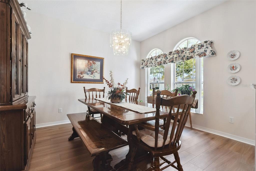 A dining room features a wooden table with a bench, chairs, and a crystal chandelier — 1209 CASTLEPORT ROAD, WINTER GARDEN, FL