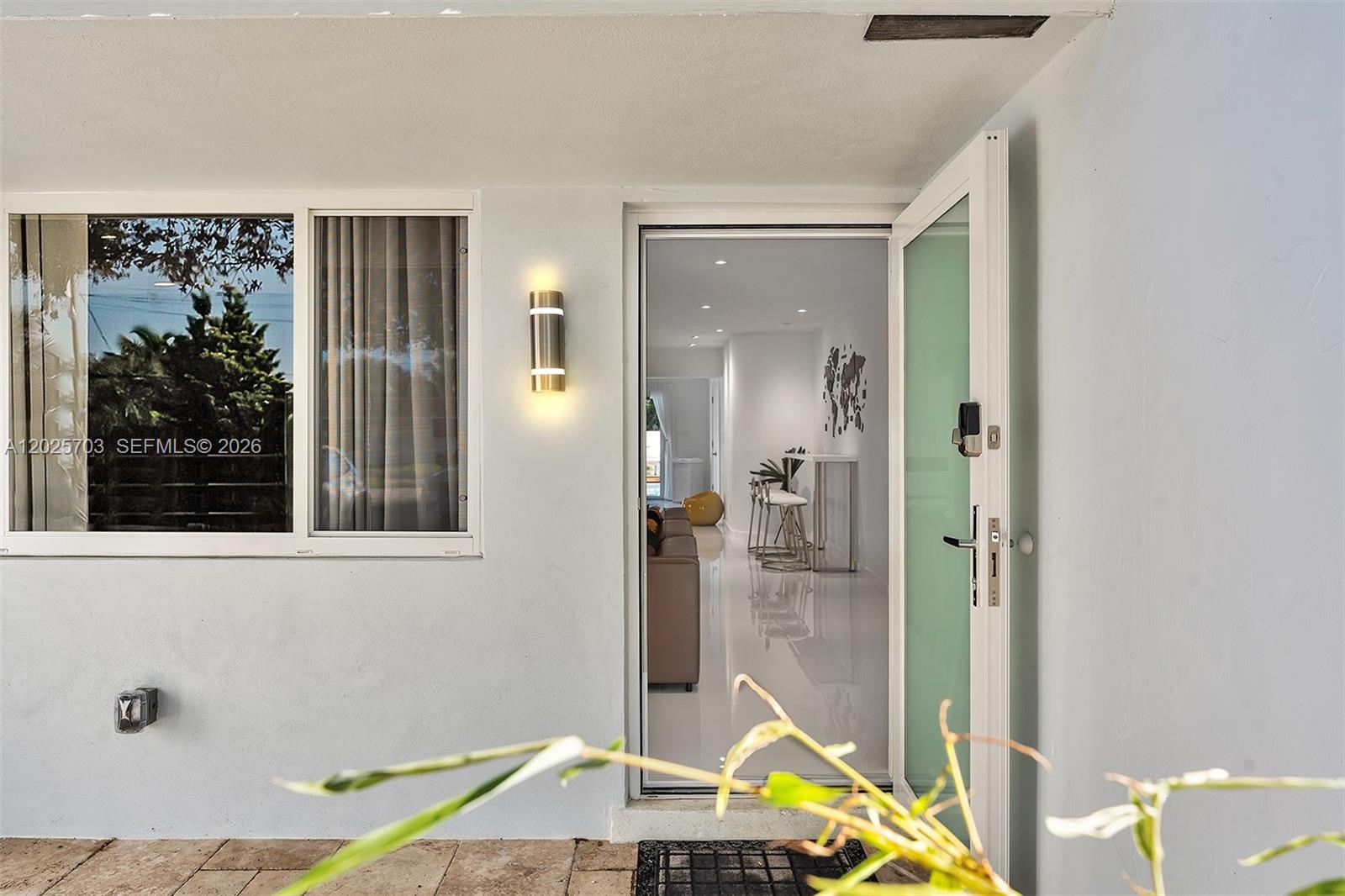 An open door reveals a bright interior with white floors, a bar area, and furniture — 5005 Johnson St, Hollywood FL 33021, HOLLYWOOD, FL