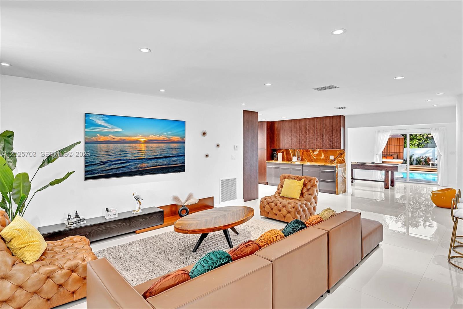 This living room features a large television, leather seating, and an open kitchen area — 5005 Johnson St, Hollywood FL 33021, HOLLYWOOD, FL