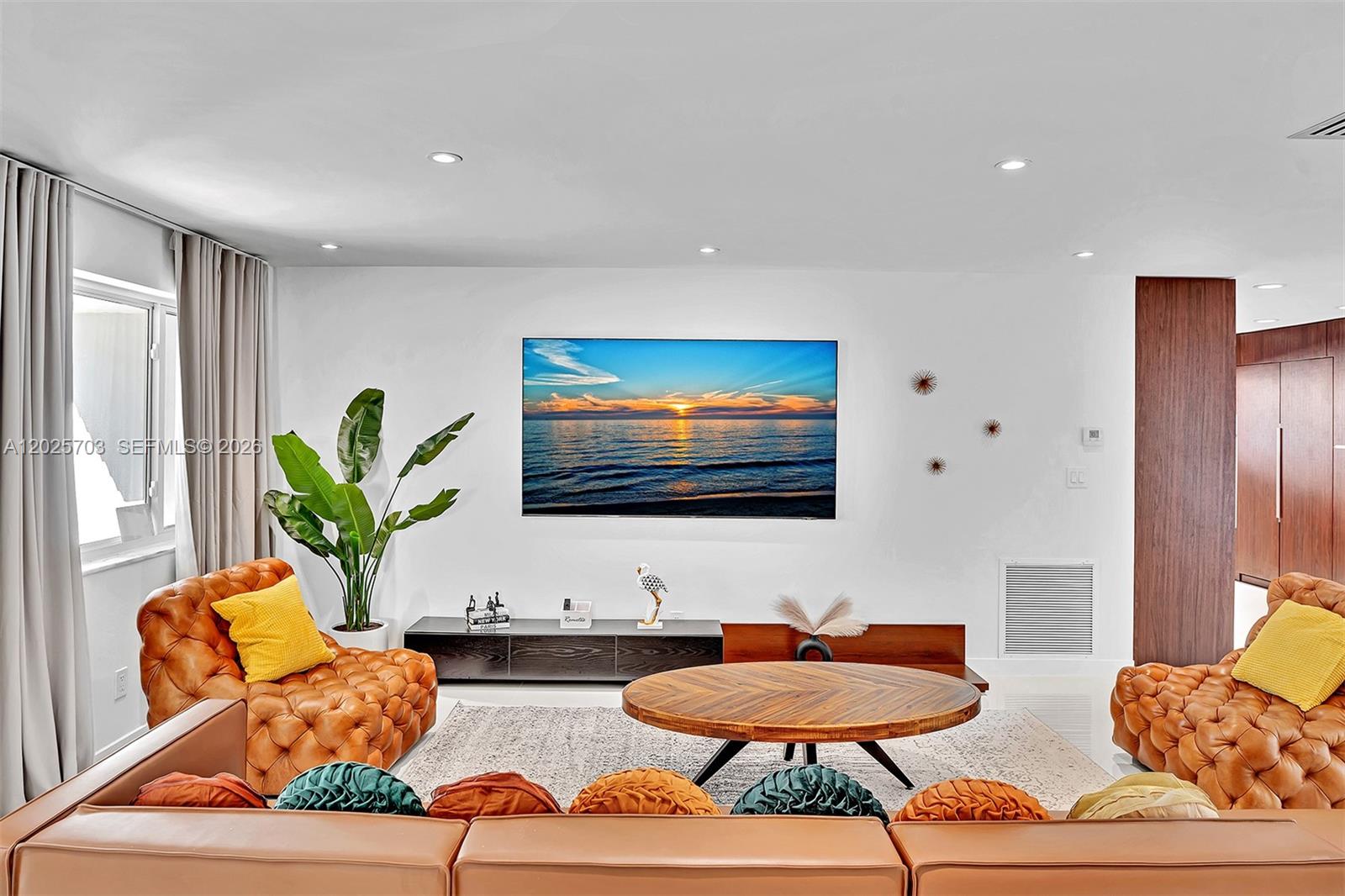 A living room features a wall-mounted television, tufted leather armchairs, and a round wooden table — 5005 Johnson St, Hollywood FL 33021, HOLLYWOOD, FL