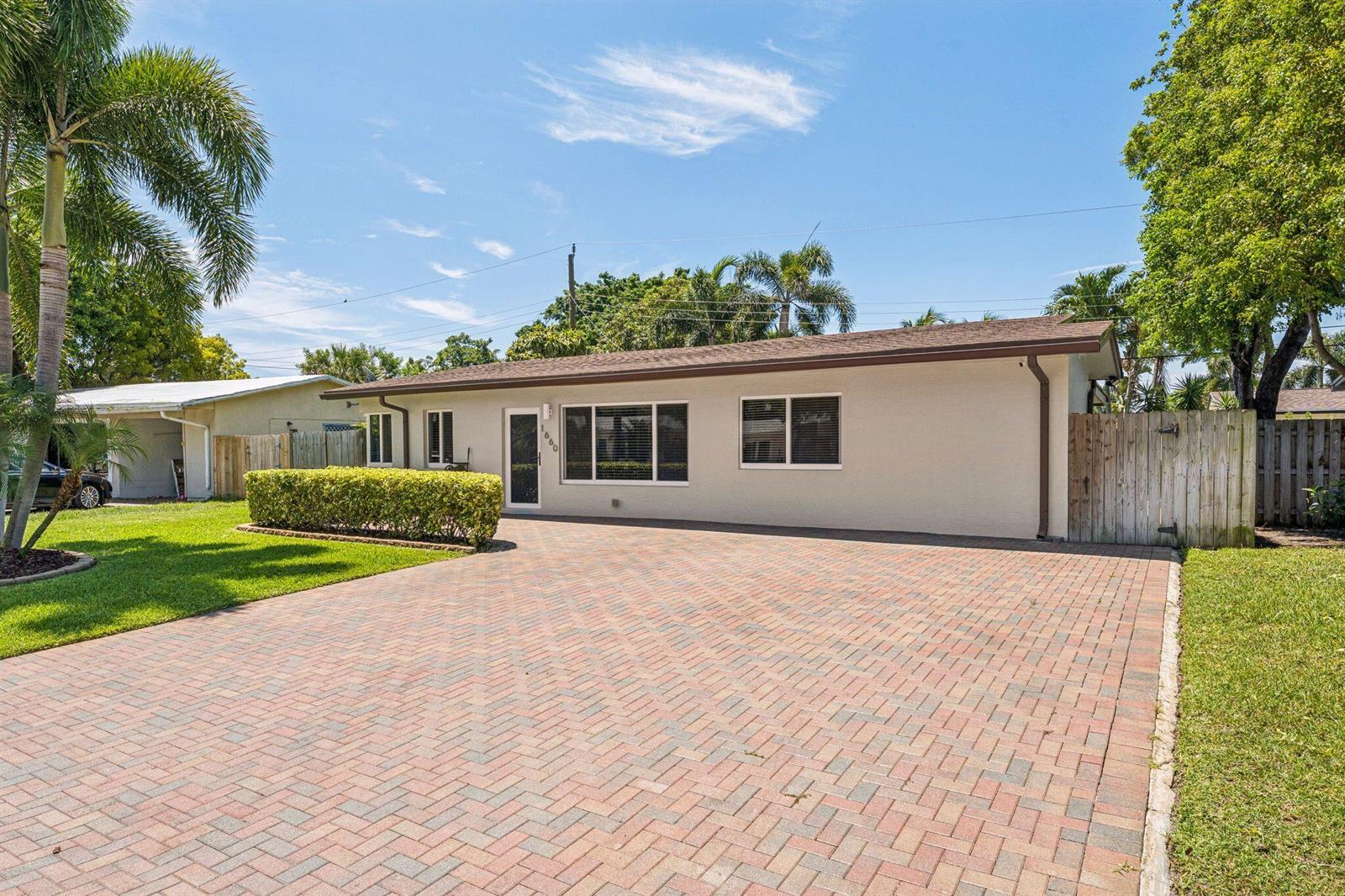 A single-story house with a brick paver driveway, a front lawn, and palm trees — 1660 NE 31st Court, Pompano Beach FL 33064, POMPANO BEACH, FL