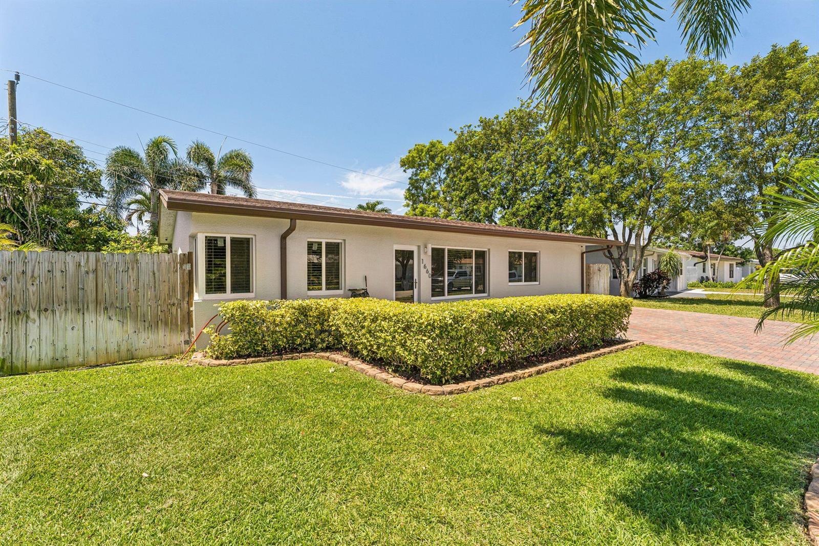 A single-story house with a light-colored exterior, a hedge, and a brick driveway — 1660 NE 31st Court, Pompano Beach FL 33064, POMPANO BEACH, FL