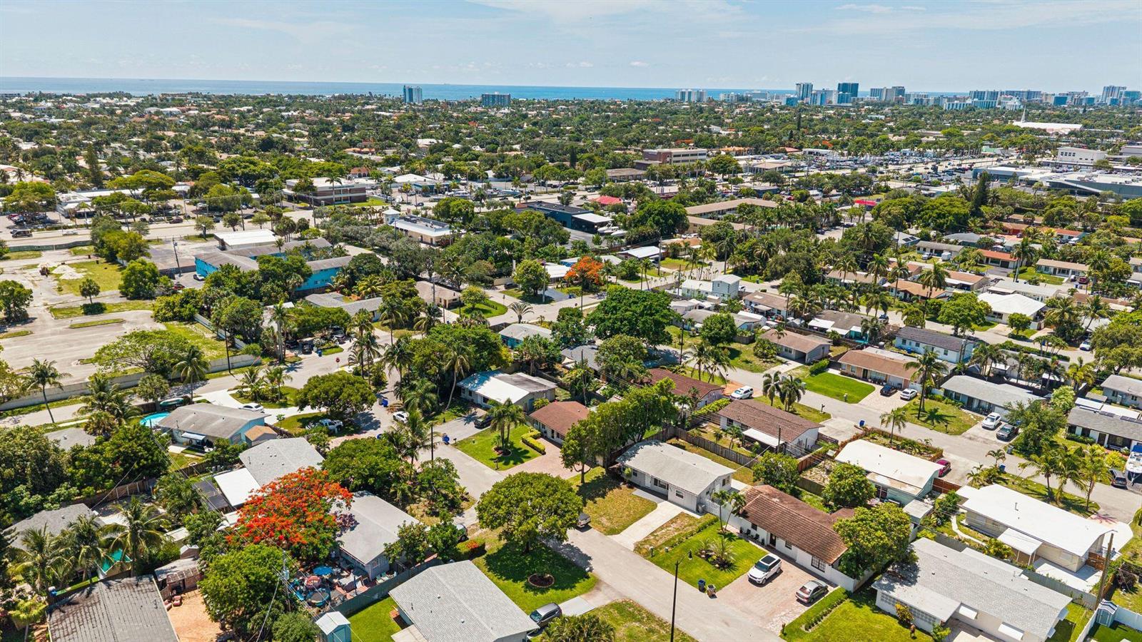 An aerial view of a residential neighborhood with houses, trees, and a distant ocean horizon — 1660 NE 31st Court, Pompano Beach FL 33064, POMPANO BEACH, FL