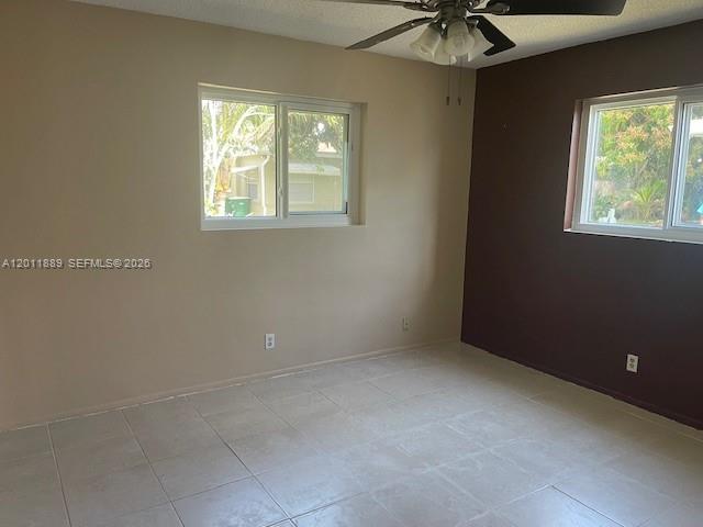 An empty room features light-colored tile floors, a ceiling fan, and two windows — 4501 Mainland Dr, Tamarac FL 33319, TAMARAC, FL