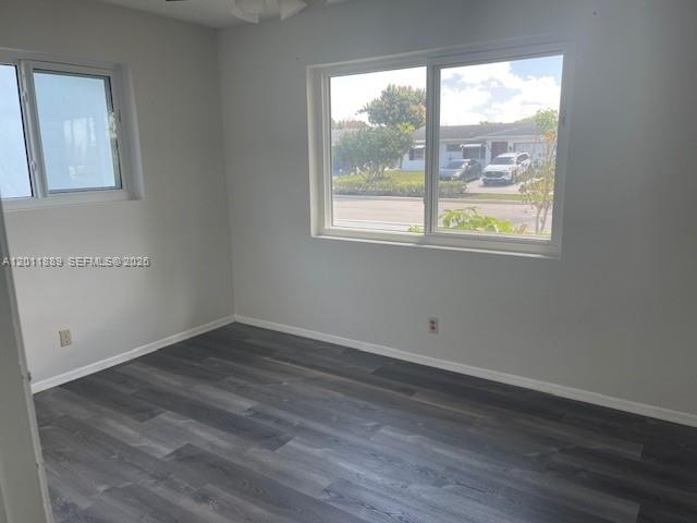 An empty room features gray wood-look flooring, light-colored walls, and two windows — 4501 Mainland Dr, Tamarac FL 33319, TAMARAC, FL
