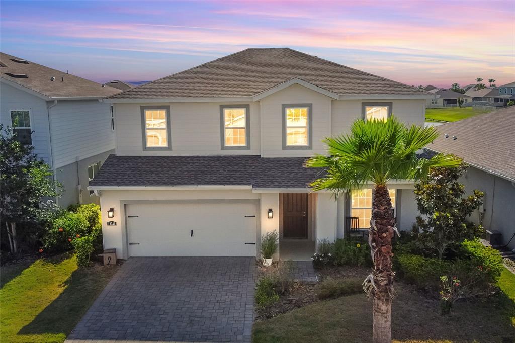 A two-story house with a paved driveway, a garage, and a palm tree in front — 12349 BLUE PACIFIC DRIVE, RIVERVIEW, FL