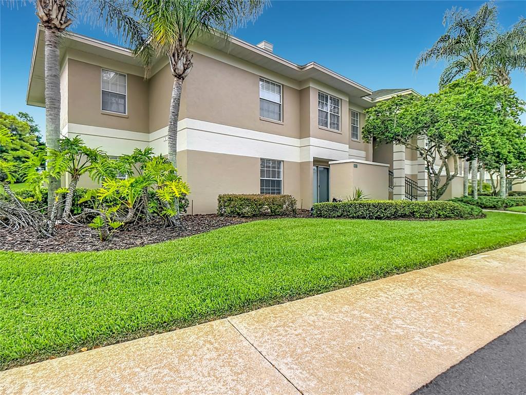A two-story tan apartment building with a manicured lawn and palm trees — 1105 EAGLE POND DRIVE UNIT 1105, WINTER HAVEN, FL