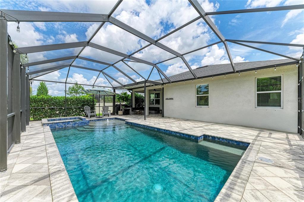 A screened-in patio features a swimming pool, a hot tub, and outdoor seating at sunset — 14405 59TH CIRCLE E, BRADENTON, FL