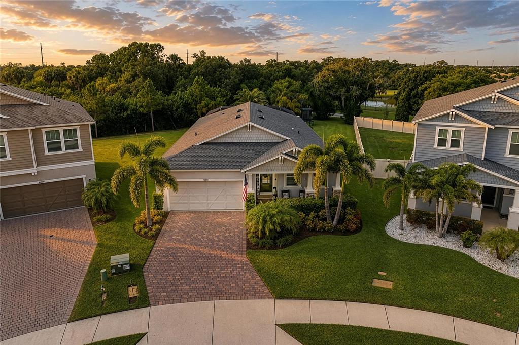 A single-story house with a paved driveway, palm trees, and a green lawn under clouds — 14405 59TH CIRCLE E, BRADENTON, FL