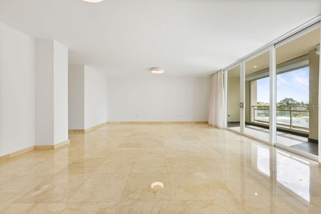 An empty room with beige marble flooring, white walls, and large sliding glass balcony doors — 20 CARRION COURT UNIT 401, SAN JUAN, PR