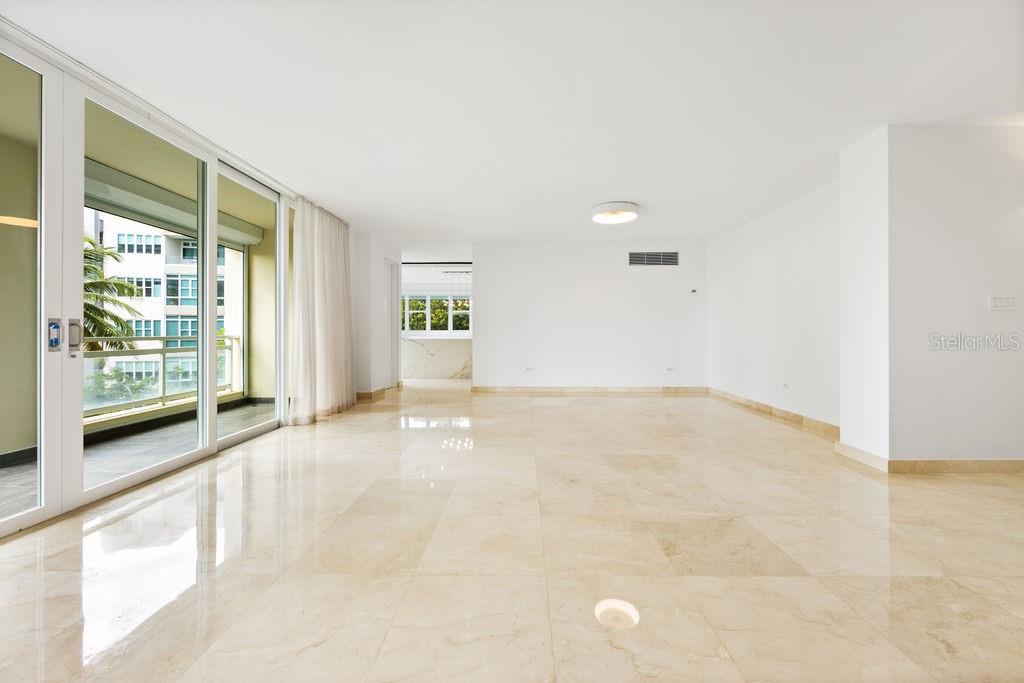 A bright, empty living room with marble floors, white walls, and sliding glass balcony doors — 20 CARRION COURT UNIT 401, SAN JUAN, PR
