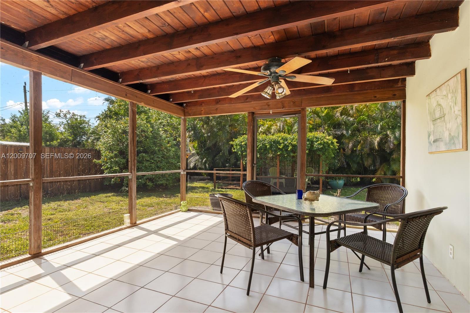 A screened-in patio features a wooden beamed ceiling, tiled floor, and a dining set — 906 NE 5th St, Hallandale Beach FL 33009, HALLANDALE BEACH, FL