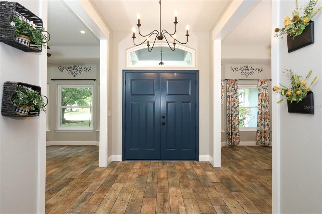 A foyer features a blue double front door, a chandelier, and wood-look tile flooring — 2461 WASSUM TRAIL, OVIEDO, FL