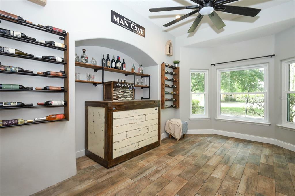 A home bar area features a wooden counter, wall-mounted wine racks, and tile flooring — 2461 WASSUM TRAIL, OVIEDO, FL