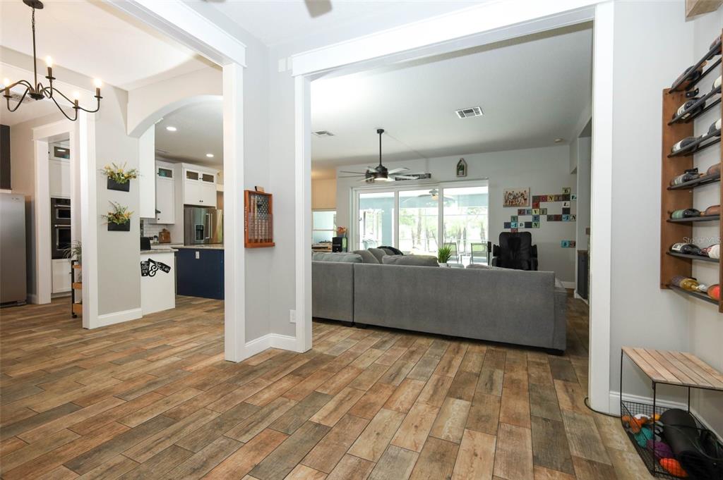 A view from a tiled hallway into a living room with a large gray sectional — 2461 WASSUM TRAIL, OVIEDO, FL