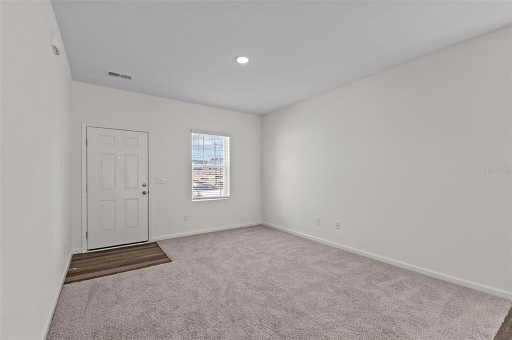 An empty room with gray carpet, white walls, a window, and a white entry door — 14626 ITALY AVENUE, DADE CITY, FL