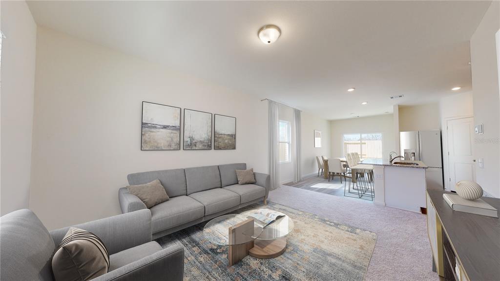 A living room with a grey sofa, armchair, coffee table, and an open kitchen area — 14626 ITALY AVENUE, DADE CITY, FL