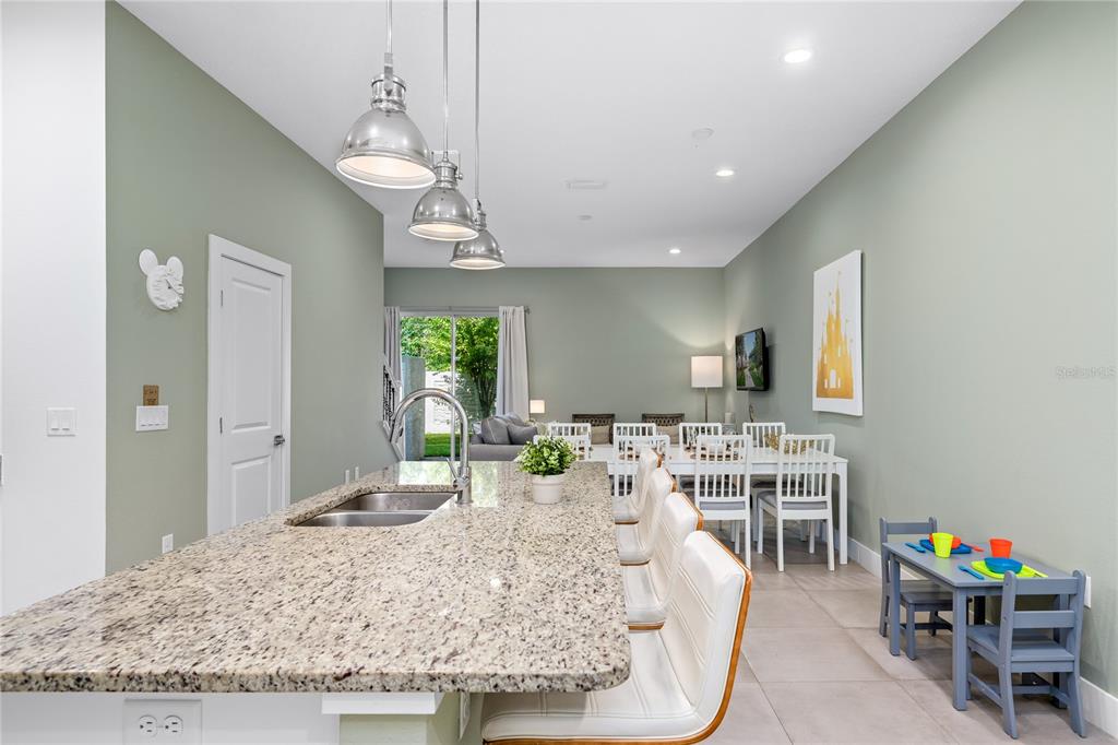 A kitchen island with granite countertops overlooks a dining area and a living room — 2614 SUNRISE SHORES DRIVE, KISSIMMEE, FL