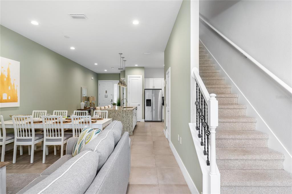 An open-concept living and dining area features light green walls, tile flooring, and stairs — 2614 SUNRISE SHORES DRIVE, KISSIMMEE, FL