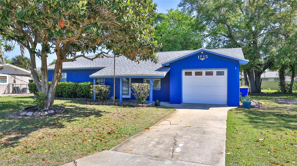 A bright blue single-story house with a white garage door and a concrete driveway — 1915 UMBRELLA TREE DRIVE, EDGEWATER, FL