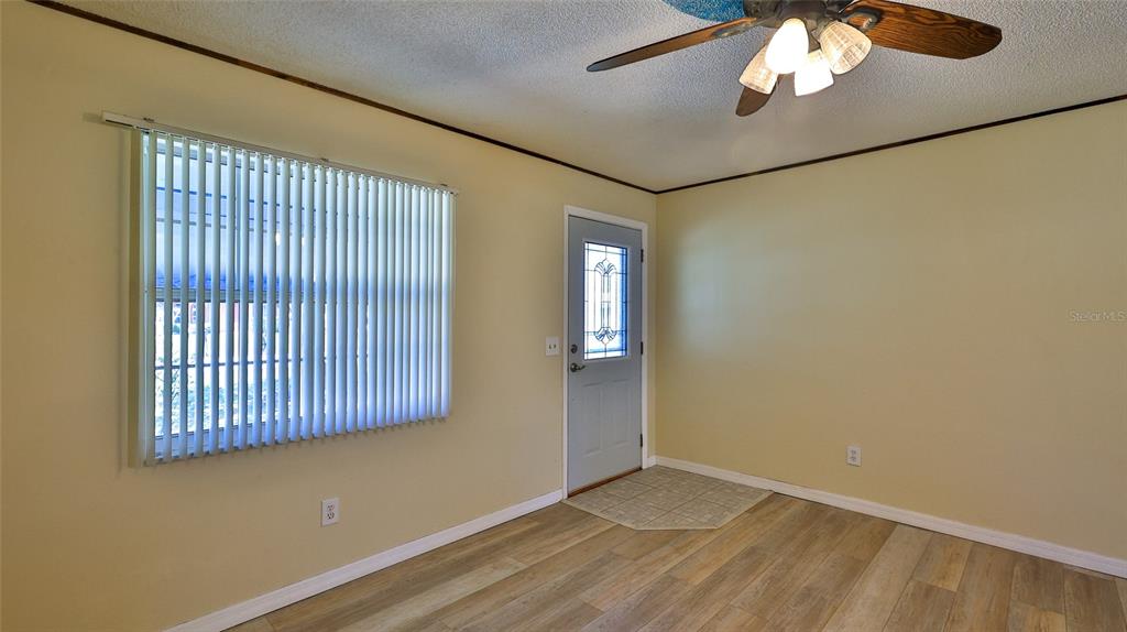 A room with light yellow walls, wood-look flooring, a ceiling fan, and a front door — 1915 UMBRELLA TREE DRIVE, EDGEWATER, FL