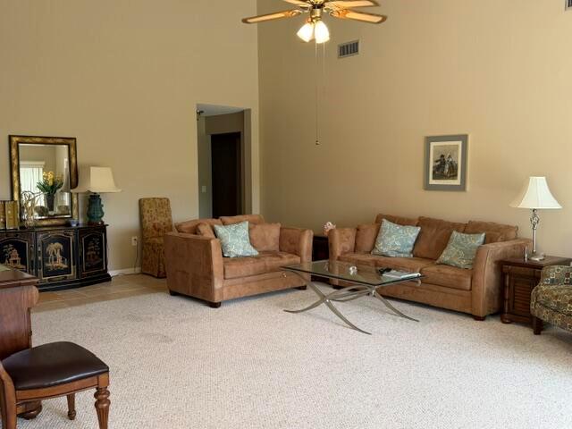 A living room features a vaulted ceiling, beige walls, tan sofas, and a glass coffee table — 254 Ridge Road, Jupiter FL 33477, JUPITER, FL