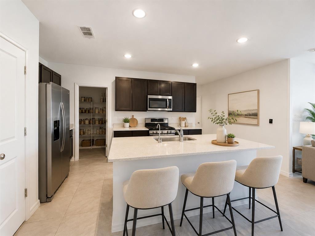 A kitchen with dark cabinets, a white island, stainless steel appliances, and a walk-in pantry — 35710 KINSEY POINT, ZEPHYRHILLS, FL