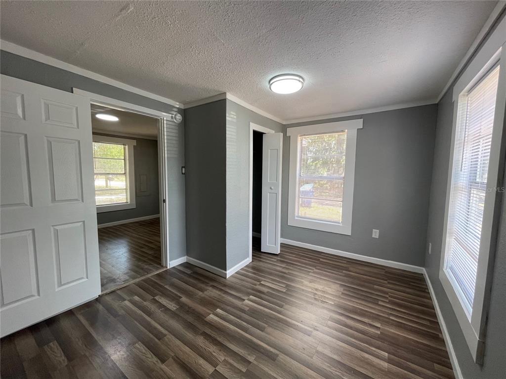 A bedroom with gray walls, wood-look flooring, two windows, and two open doorways — 630 N NASHUA AVENUE, FORT MEADE, FL