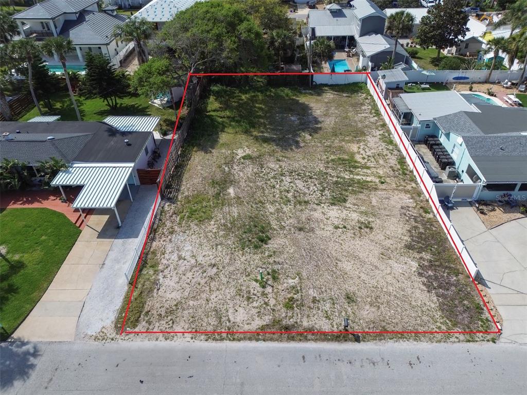 An aerial view shows a vacant, rectangular residential lot outlined in red between two houses — 209 NORMANDY AVENUE, NEW SMYRNA BEACH, FL