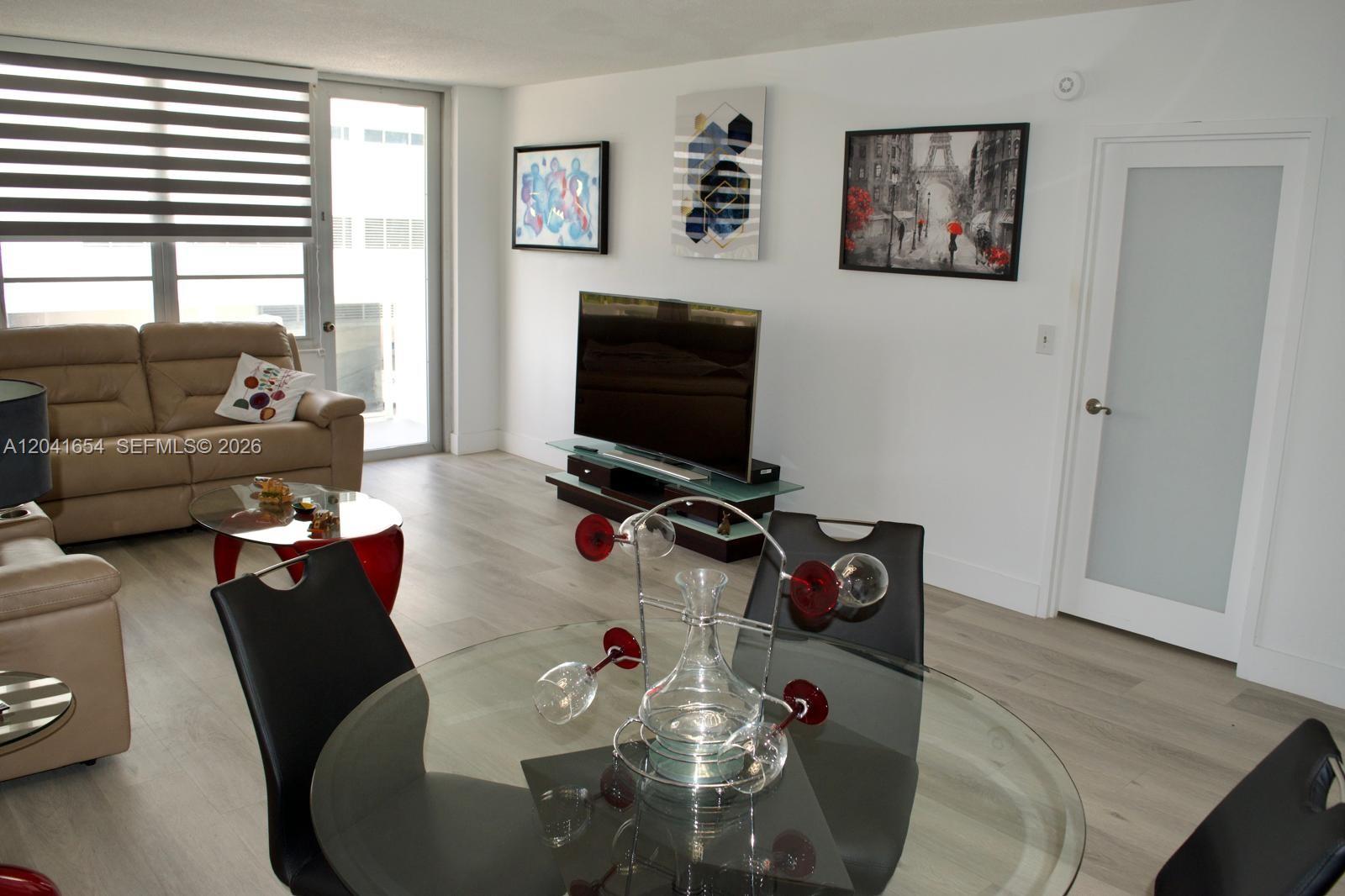 A living and dining area features light wood flooring, a glass table, and wall art — 3725 S Ocean Dr # 423, Hollywood FL 33019, HOLLYWOOD, FL