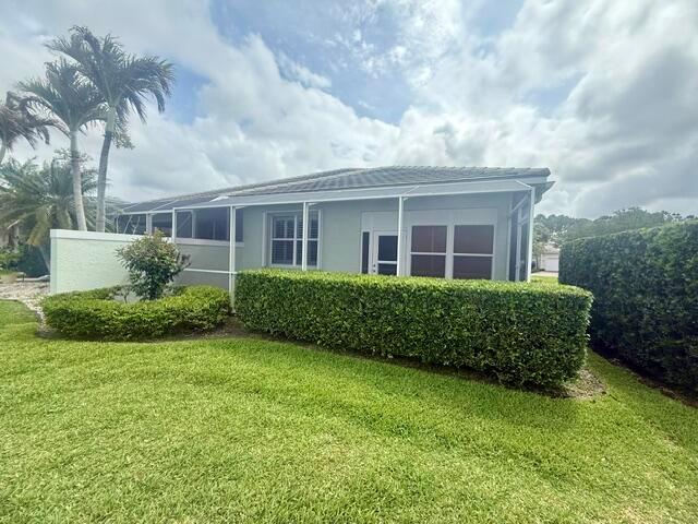 A light-colored house features a screened-in patio, manicured hedges, and palm trees on a lawn — 4645 SE Bridgetown Court, Stuart FL 34997, STUART, FL