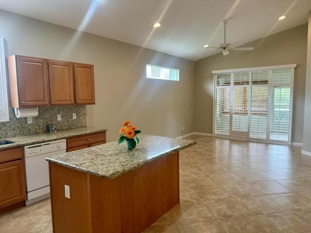 A kitchen with wood cabinets and a granite island opens into a spacious living area — 4645 SE Bridgetown Court, Stuart FL 34997, STUART, FL