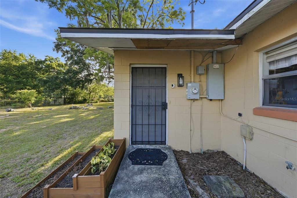 A concrete block exterior wall features a metal security door under a flat roof overhang — 218 S EAST STREET, LEESBURG, FL