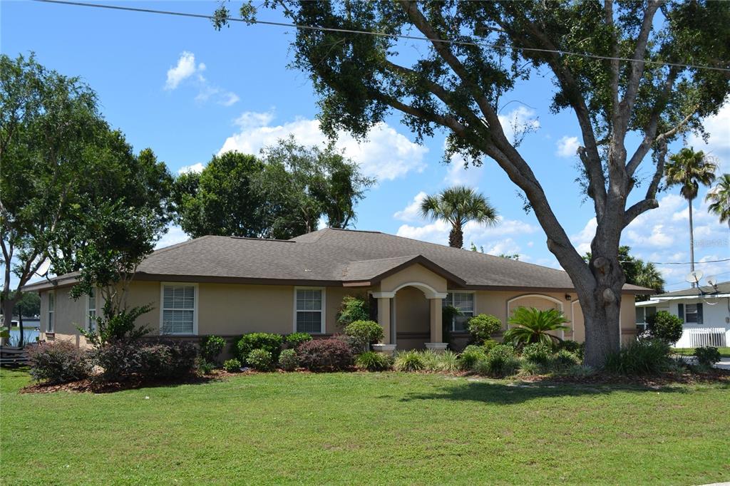A single-story tan house with a brown roof and a large tree in the front yard — 26 SE OCALE WAY, SUMMERFIELD, FL