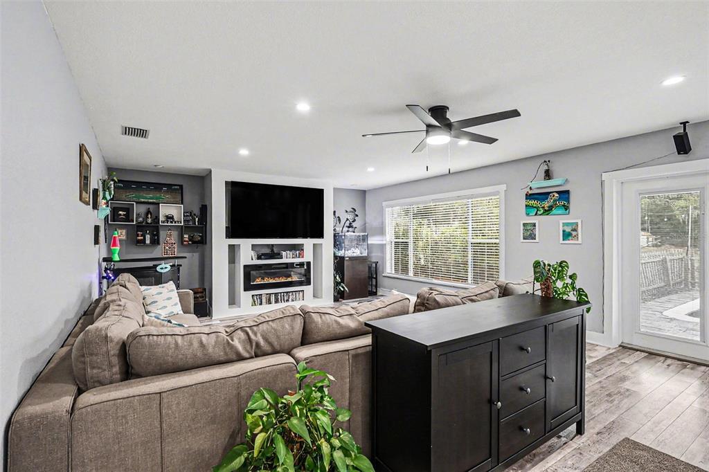 A living room features a sectional sofa, a dark wood console, and a wall-mounted television — 1713 14TH AVENUE W, PALMETTO, FL
