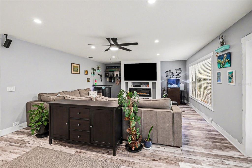 A spacious open-concept living room features a large sectional sofa and wood-look flooring — 1713 14TH AVENUE W, PALMETTO, FL