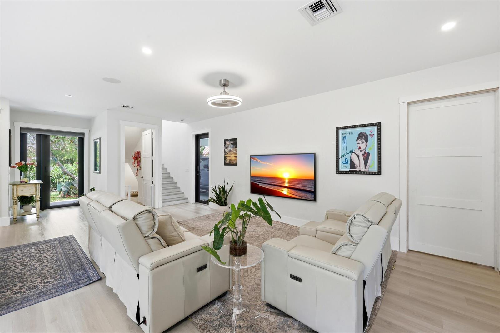 A living room features white leather sofas, a wall-mounted television, and light wood flooring — 740 Winters Street, West Palm Beach FL 33405, WEST PALM BEACH, FL